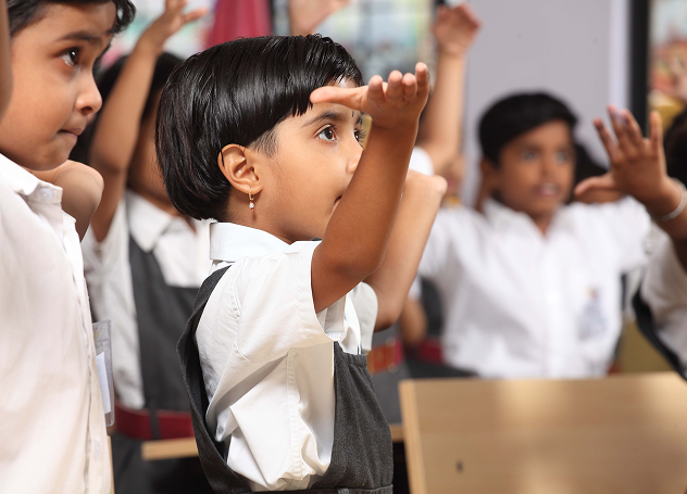 Children raising hands in class